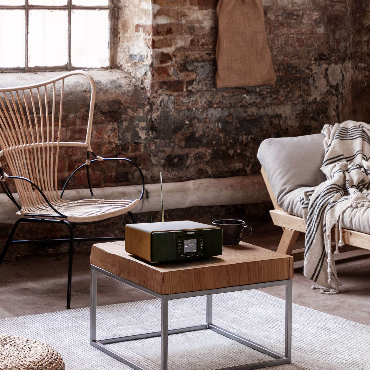 Modern living room with wooden coffee table, wicker chair, and brick wall.