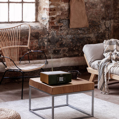 Modern living room with wooden coffee table, wicker chair, and brick wall.