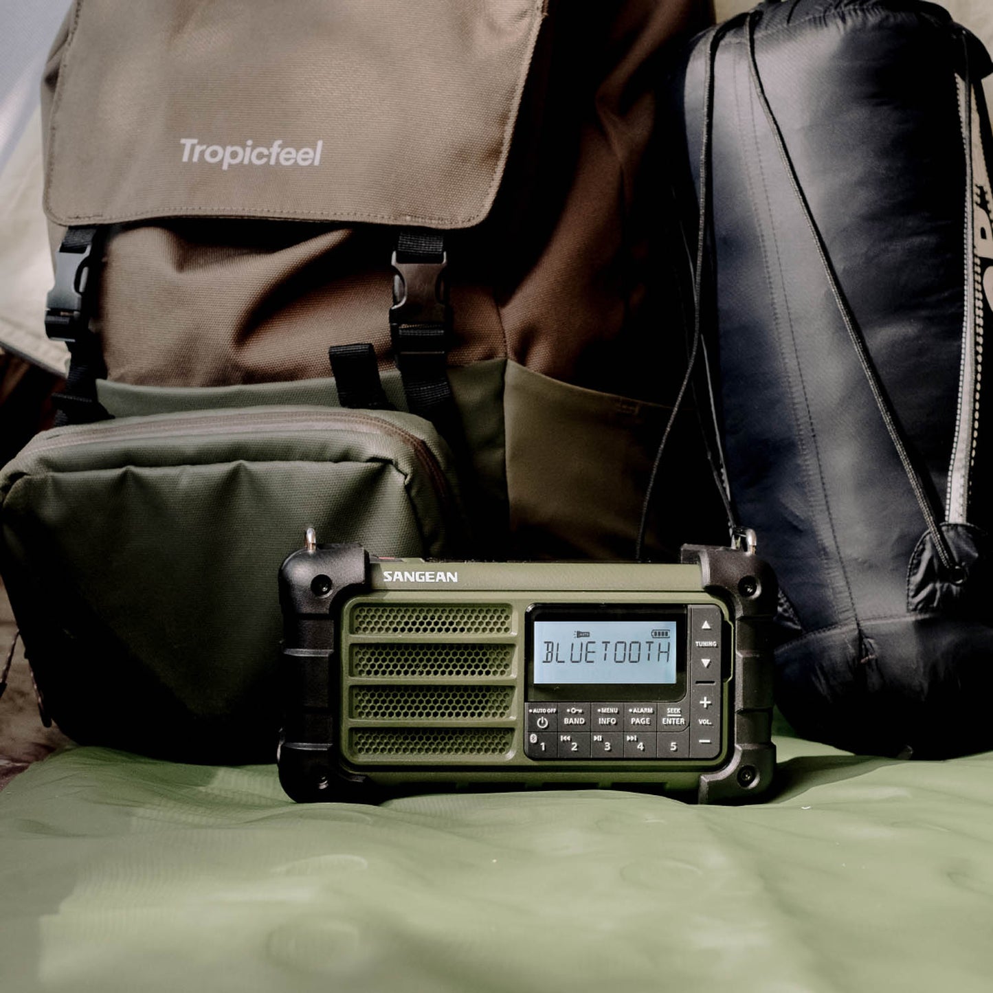 Portable radio with Bluetooth display on a surface with bags in the background
