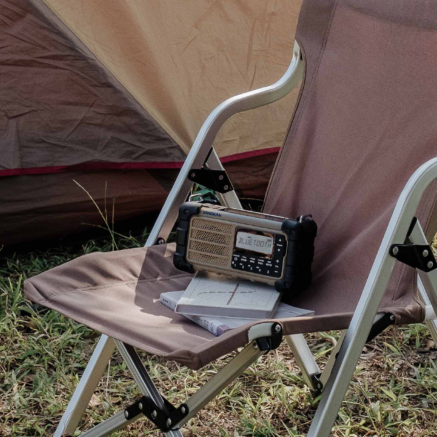 Camping chair with a radio and notebook in front of a tent