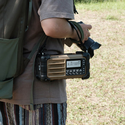 Person holding a Sangean radio in an outdoor setting