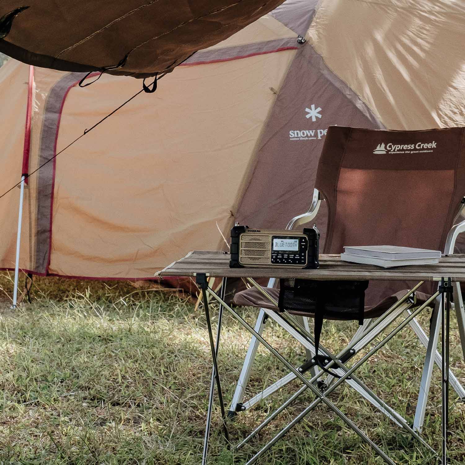 Camping scene with a tent, table, and chair in a grassy area