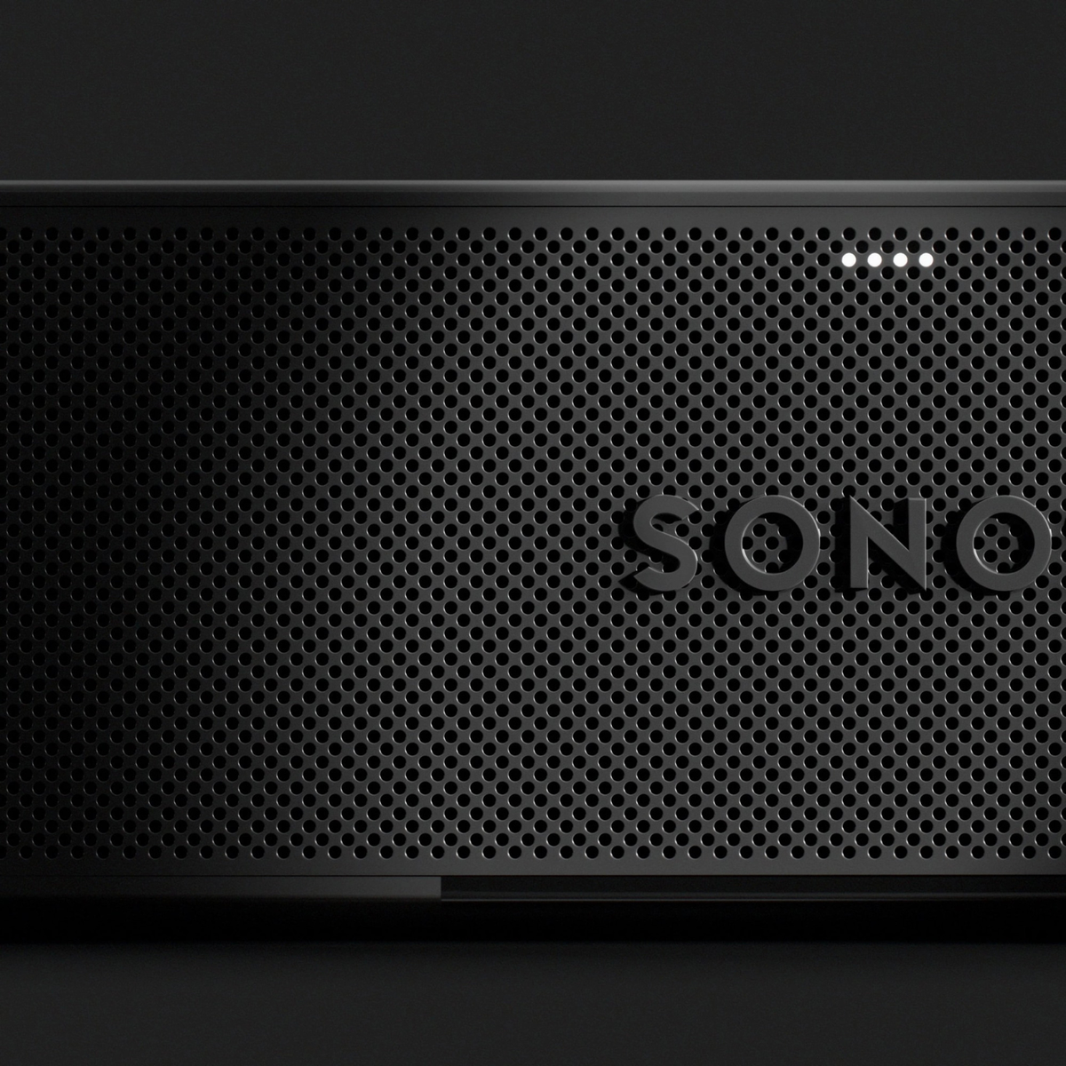 Close-up of a black Sonos speaker front grille with the embossed SONO logo and four small illuminated indicator lights, shown against a dark background.