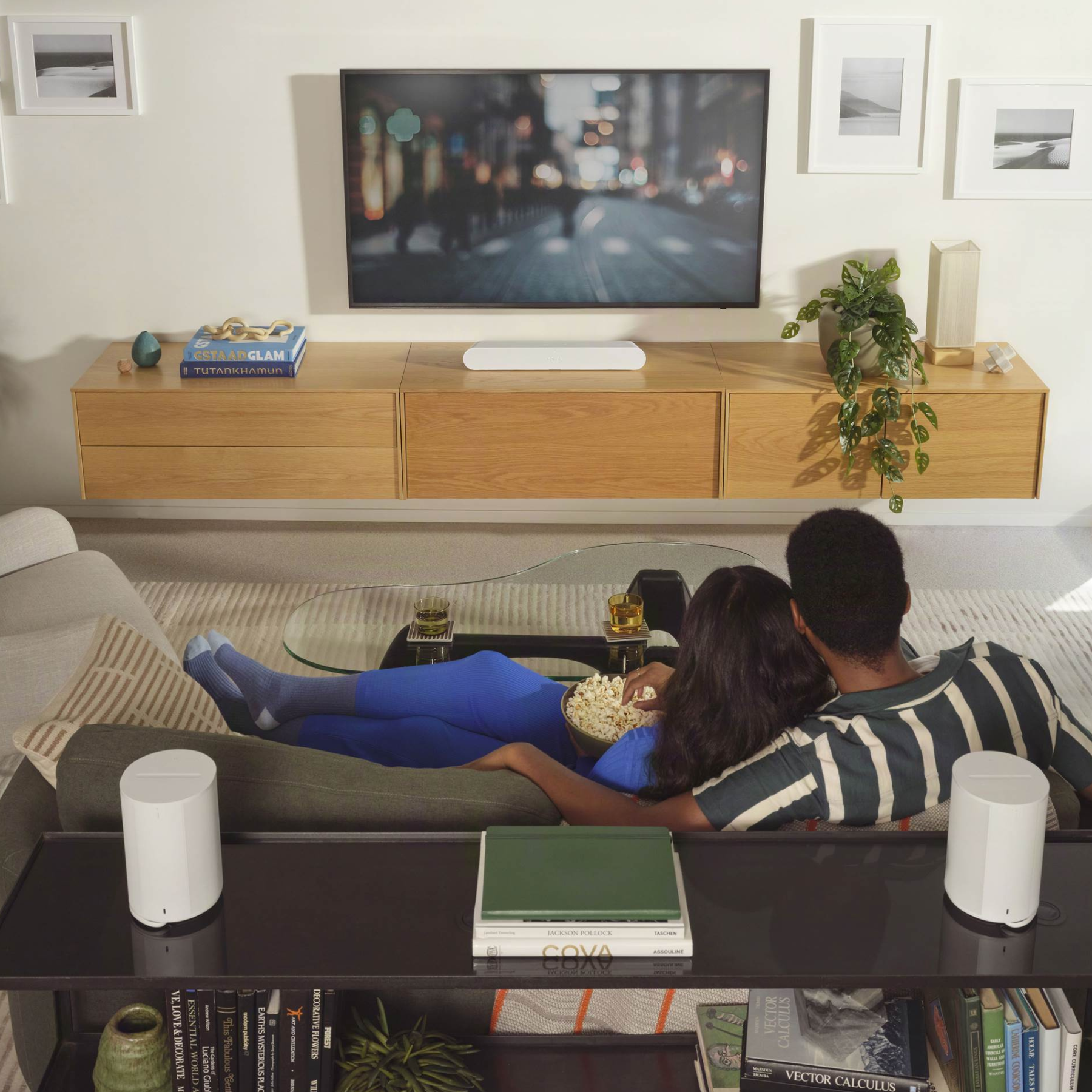 Couple watching TV in a modern living room with wooden cabinet and decor.