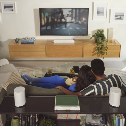 Couple watching TV in a modern living room with wooden cabinet and decor.