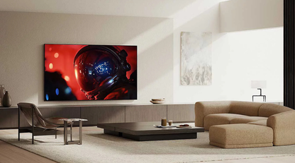 A large wall-mounted television displaying a red astronaut helmet scene, set in a modern living room with beige seating, a low black coffee table, and neutral walls.