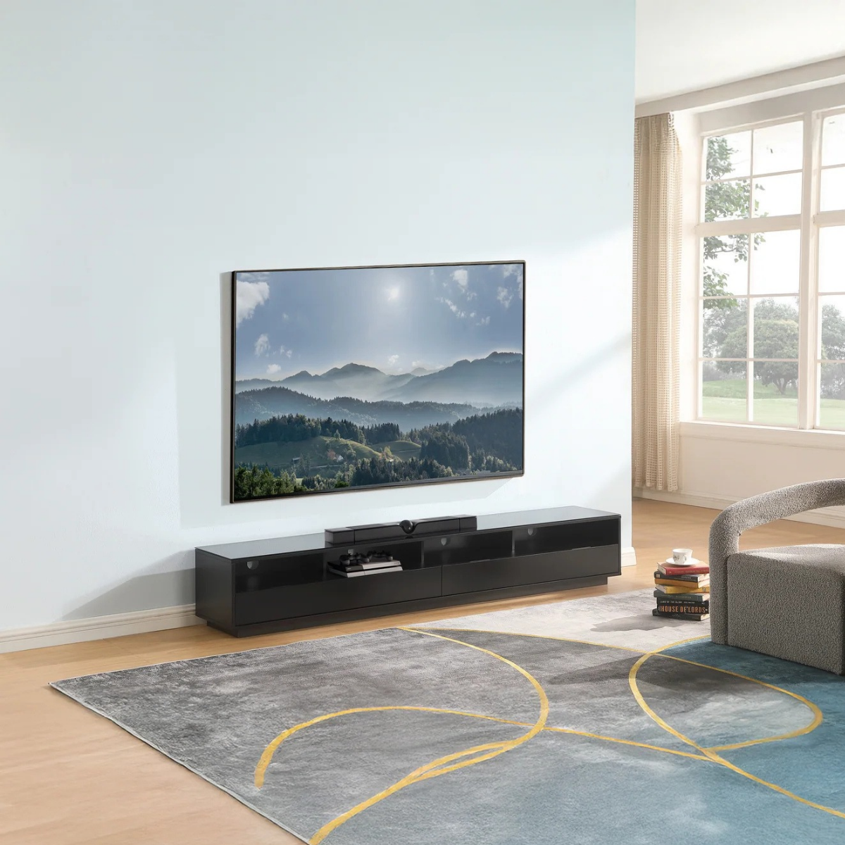A modern living room scene featuring a black media console with a large flat-screen TV displaying a mountain landscape. 