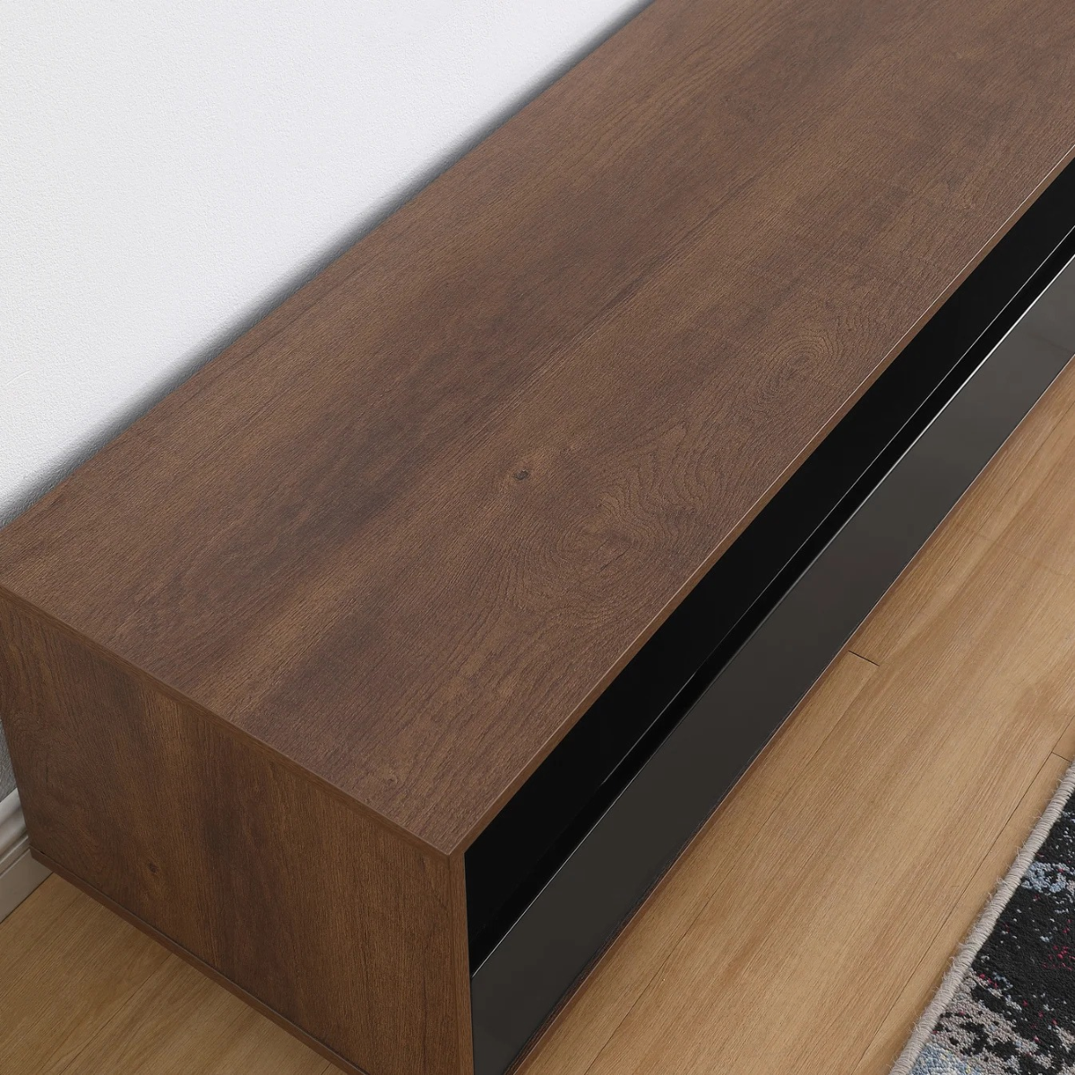 Wooden console table with black base on a light wood floor.