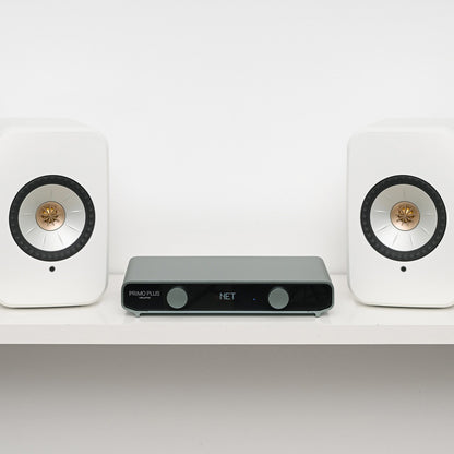 Two white speakers with a black audio receiver on a white shelf