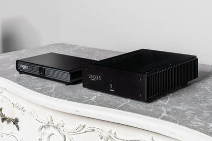 Two black audio equipment devices, displayed on a gray marble surface against a light gray wall.