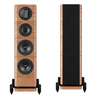 A pair of floorstanding tower speakers shown from the front and side, featuring a light brown wood grain finish with black cones and black mounting feet, set against a plain white background.