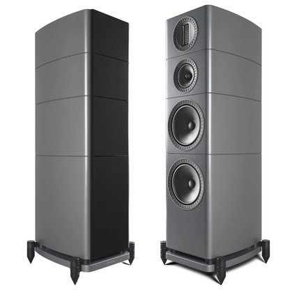 Two grey floorstanding speakers shown on a white background, one from the side and one from the front three-quarter angle, both on black speaker stands.