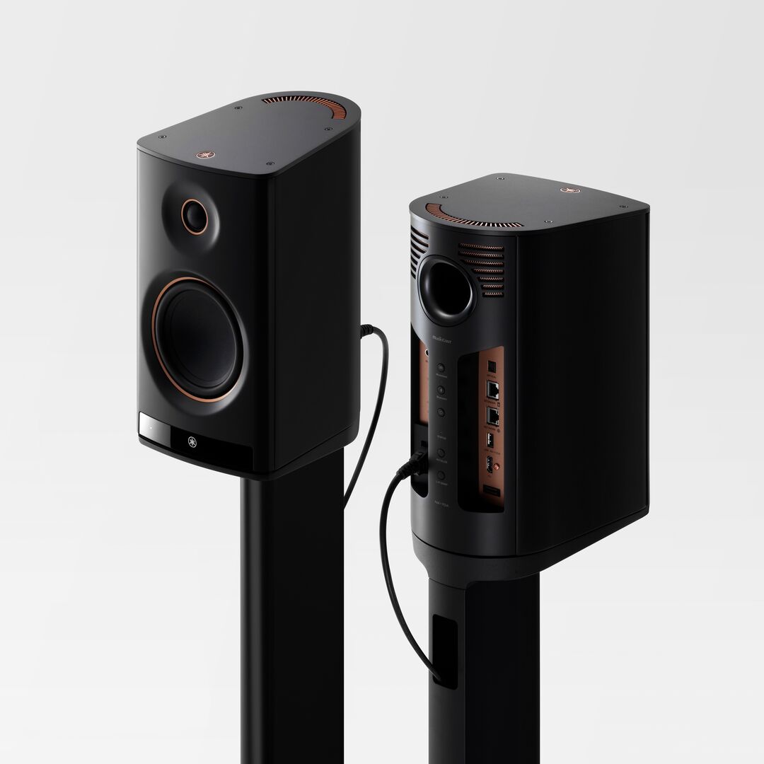Two black Yamaha NX-70A Wireless Speakers on stands against a grey background