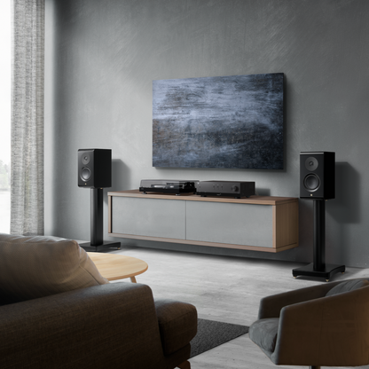 A modern living room setup featuring a wall-mounted abstract canvas print above a floating wood and gray media console with a turntable and receiver, flanked by two black speakers on stands.